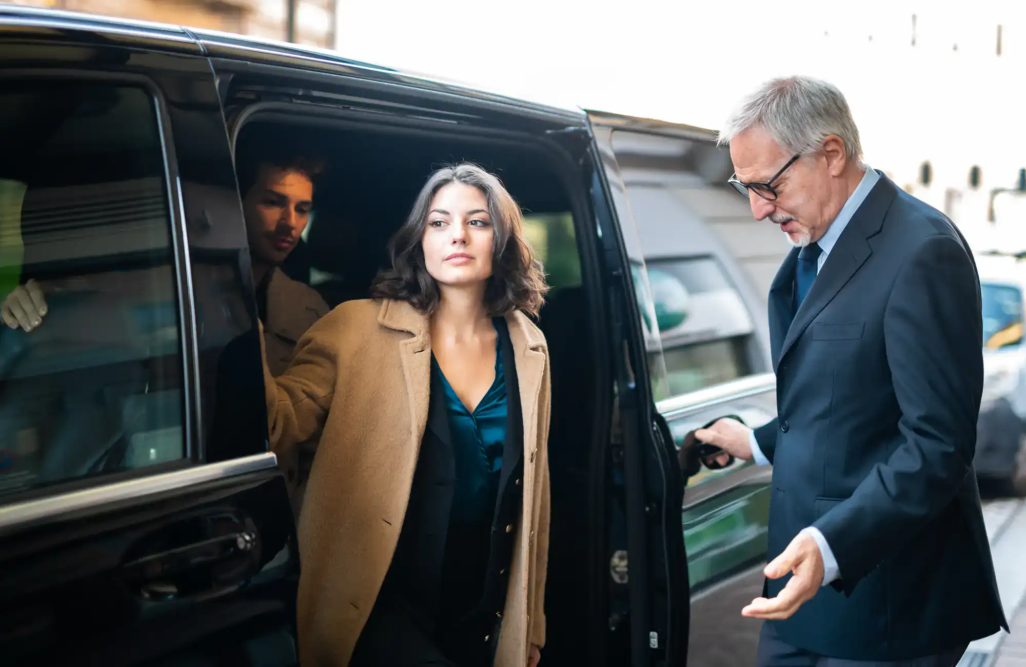 Philadelphia airport shuttle service picking up passengers at the arrivals area, with travelers handling bags and a chauffeur assisting, representing smooth, reliable airport transportation