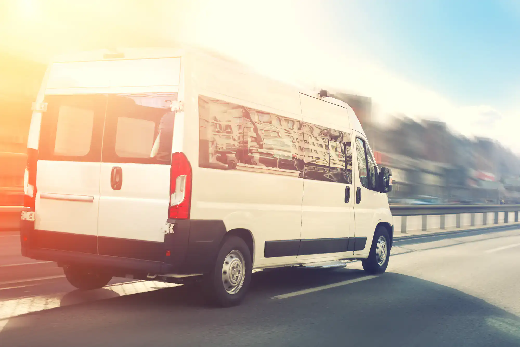 A Philadelphia Car and Limo airport shuttle van driving along city streets in Philadelphia County, PA, transporting passengers safely to and from the airport with professional service