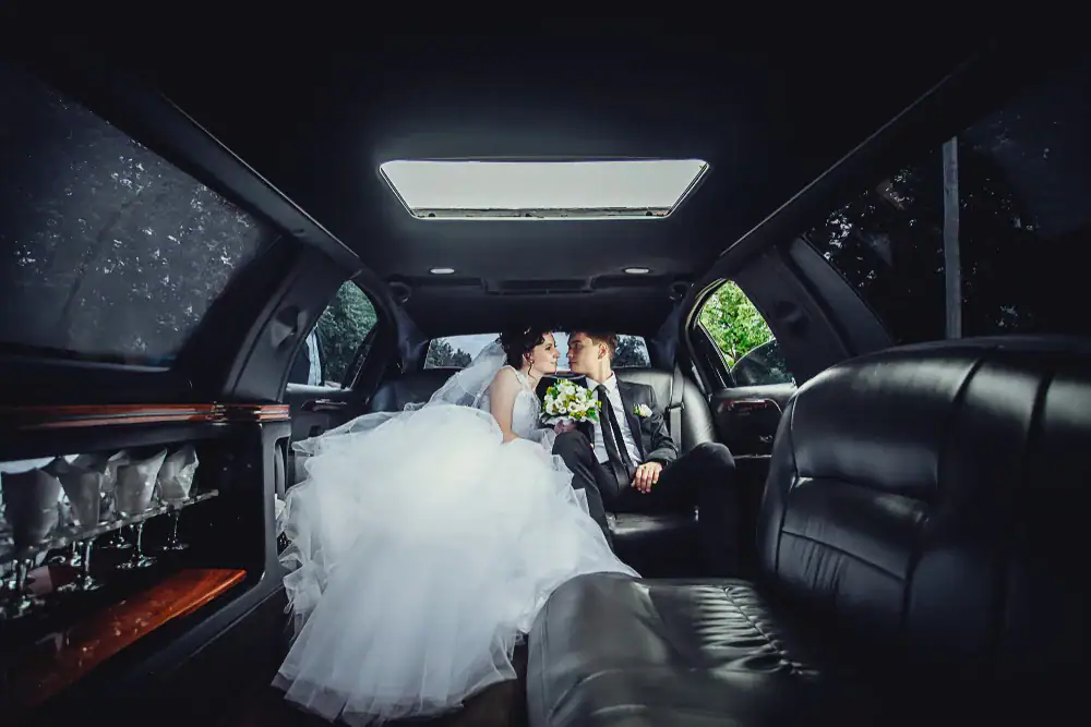 Bride and groom sharing a romantic kiss outside a luxury limousine in Philadelphia County, Pennsylvania, celebrating their special day with Philadelphia Car and Limo service
