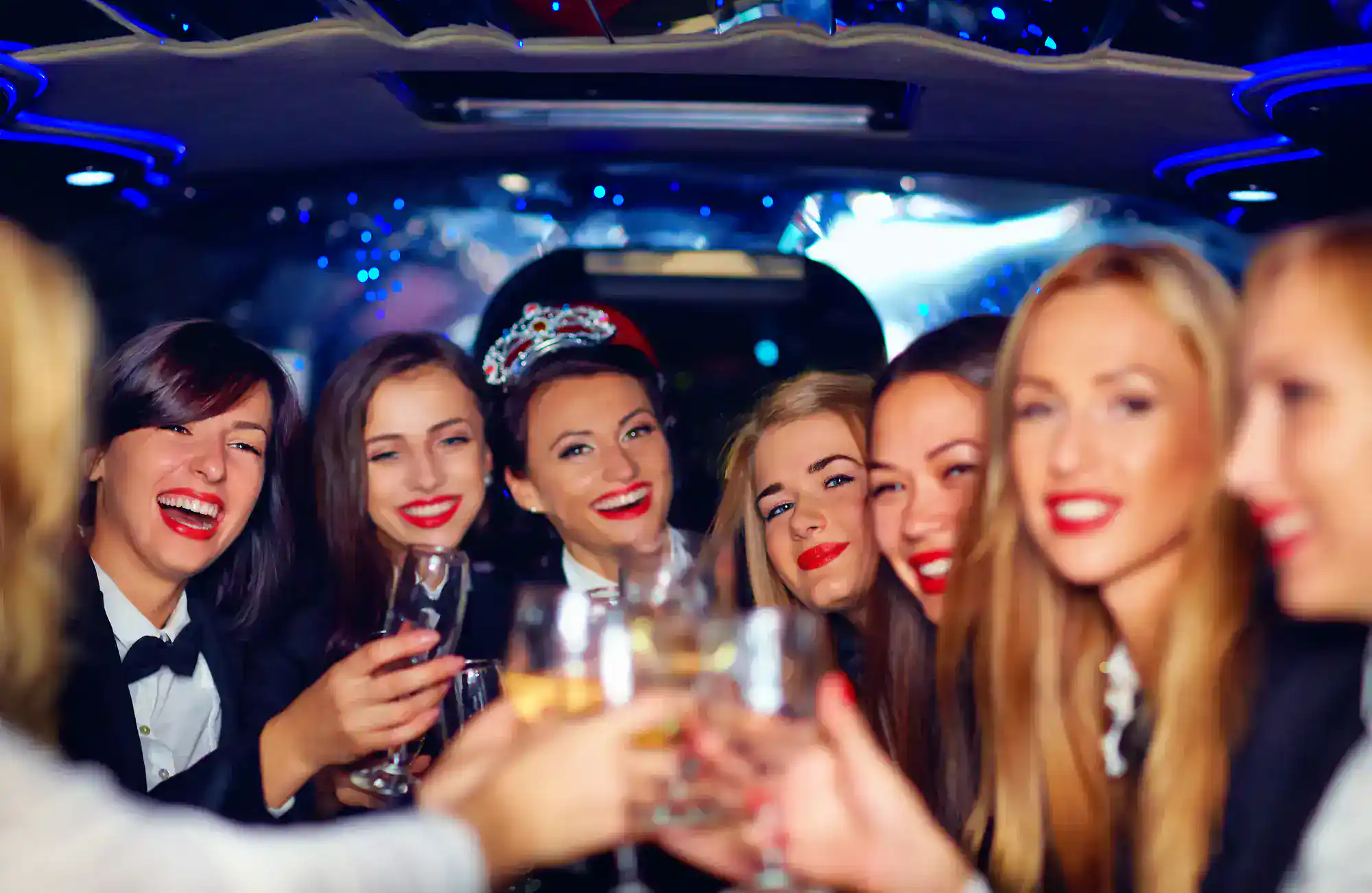 A group of excited high school students posing by a sleek limousine, smiling and dressed in prom outfits, capturing the festive atmosphere of a Philadelphia prom celebration